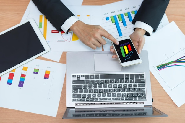 Homme d'affaires asiatique travaillant sur le bureau avec un ordinateur portable, une tablette et un téléphone intelligent de la vue de dessus