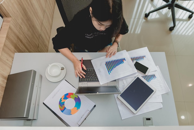 Homme d'affaires asiatique travaillant sur le bureau avec un ordinateur portable, une tablette et un téléphone intelligent de la vue de dessus