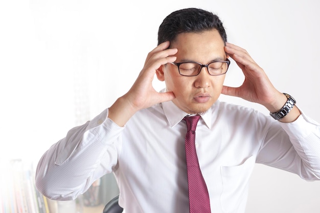 Homme d'affaires asiatique travaillant sur un ordinateur portable au bureau Geste de stress fatigué