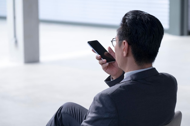 Homme d'affaires asiatique utilisant un téléphone portable pour laisser un message vocal