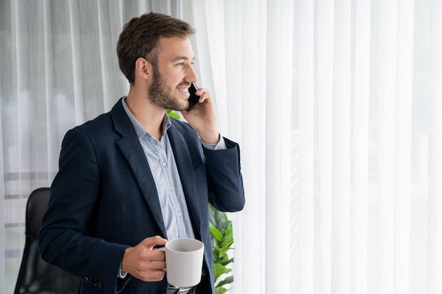 Homme d'affaires assidu debout dans un bureau moderne parlant au téléphone Entité