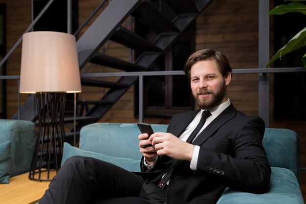 homme d'affaires assis dans un restaurant élégant dans un costume d'affaires relaxant et utilise le téléphone pour communiquer