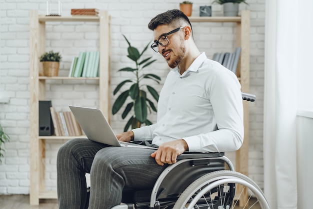 Homme d'affaires assis en fauteuil roulant et utilisant un ordinateur portable à la maison