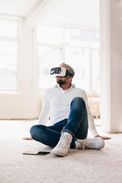 Homme d'affaires assis sur le sol, à l'aide de lunettes VR