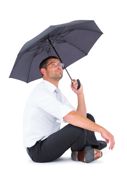 Homme d&#39;affaires assis sur le sol avec un parapluie noir