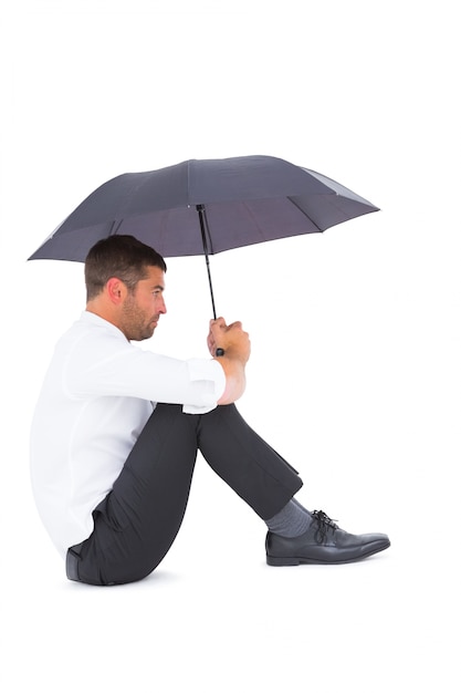 Homme d&#39;affaires assis sur le sol avec un parapluie noir