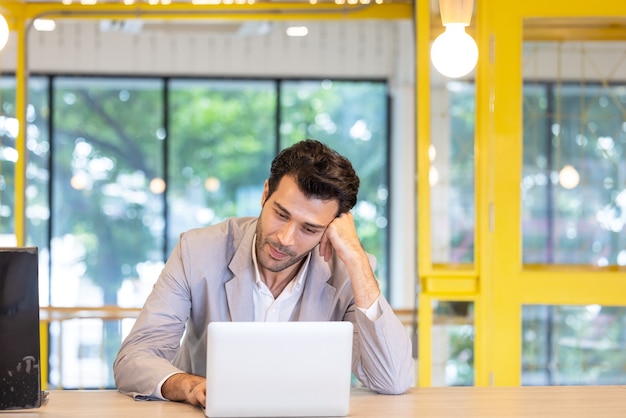 Homme d'affaires attirant utilisant un ordinateur portable dans son bureau d'espace ouvert