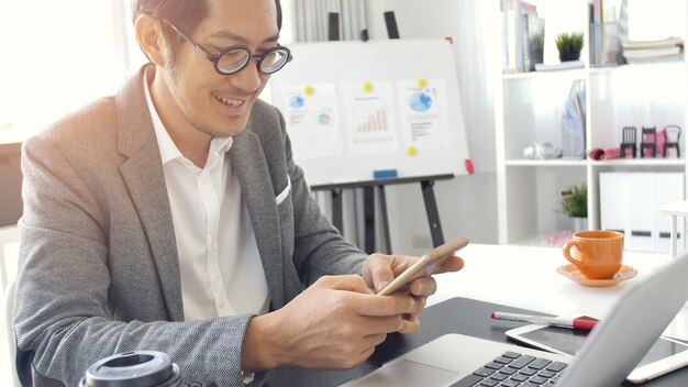 Homme d&#39;affaires au bureau avec ordinateur portable et téléphone portable,