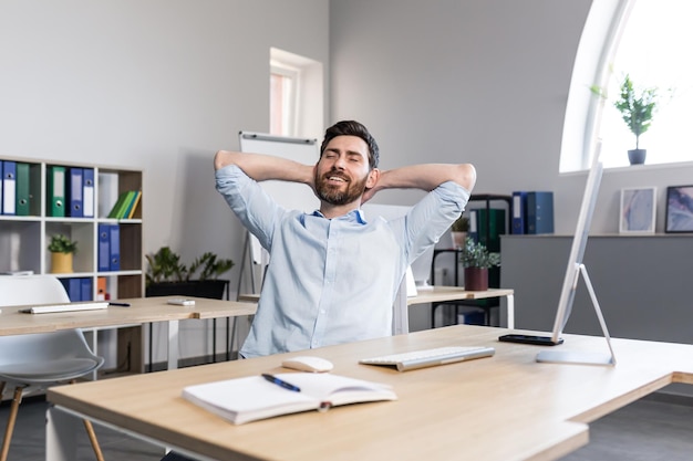 Homme d'affaires au bureau se reposant rêveusement en jetant ses mains derrière sa tête homme travaillant sur un projet d'entreprise