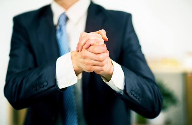 Homme d'affaires au bureau avec ses mains jointes. Volonté d'amitié et de coopération.