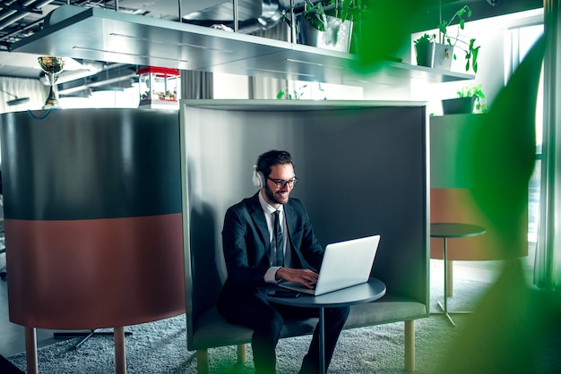 Homme d'affaires au bureau travaillant sur ordinateur portable, directeur des ventes en ligne avec des écouteurs.