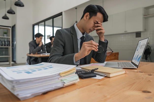 Homme d'affaires au travail sur son ordinateur portable tout en souffrant de maux de tête et d'anxiété avec un travail tout en luttant contre le stress de la fatigue