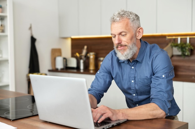 Un homme d'affaires aux cheveux gris et sérieux qui utilise un ordinateur portable.
