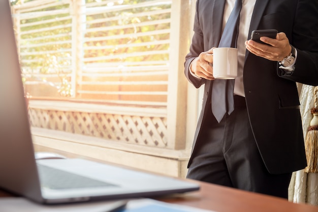 Homme d&#39;affaires ayant une pause-café et regardant un téléphone cellulaire.