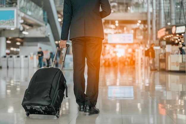 Homme d'affaires avec bagage à main marchant dans le terminal de l'aéroport. Homme d'affaires portant une valise en marchant dans un terminal de départ de passagers à l'aéroport. Voyage d'affaires voyage voyageur d'affaires.