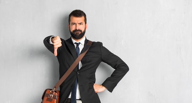 Homme d&#39;affaires avec barbe montrant le pouce vers le bas de signe avec une expression négative