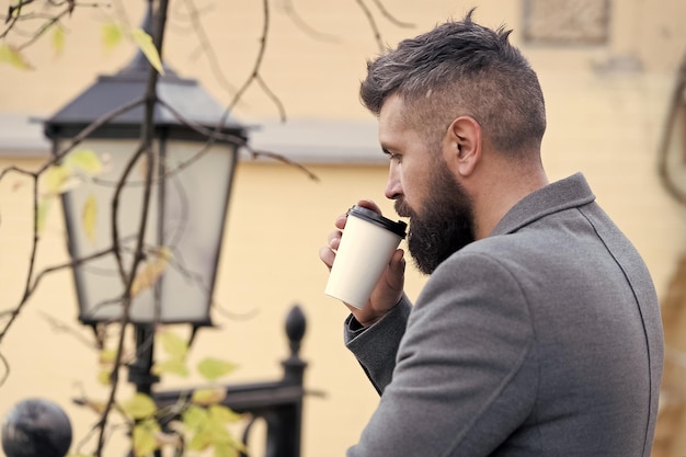 Homme d'affaires barbu boire du café à l'extérieur Hipster tenir une tasse de café en papier et profiter de l'environnement du parc Pause café relaxante Buvez-le sur le pouce L'homme barbu hipster préfère le café à emporter