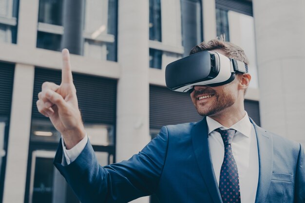 Homme d'affaires barbu souriant avec du chaume portant des lunettes vr regardant quelque chose en réalité virtuelle