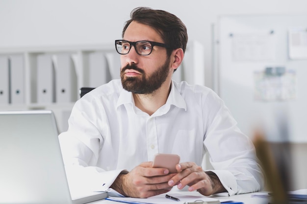 Homme d'affaires barbu tenant un téléphone intelligent