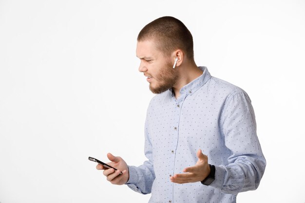 L'homme d'affaires barbu utilise des écouteurs sans fil et un smartphone
