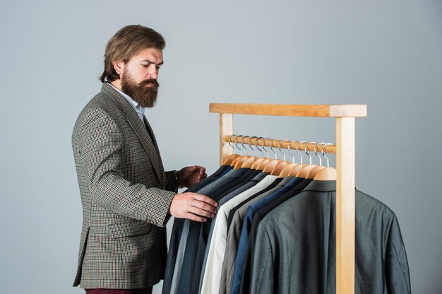 Homme d'affaires beau mec dans un magasin de vêtements choisissant des vêtements exigeant un concept client