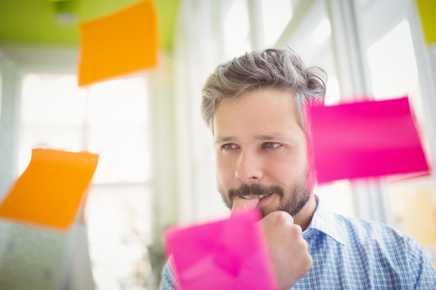 Homme d'affaires bien pensé regardant des notes adhésives