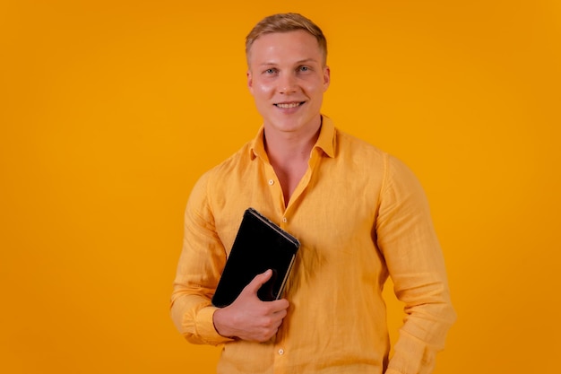 Homme d'affaires blond caucasien sur fond jaune portrait avec une tablette souriant PDG d'une entreprise