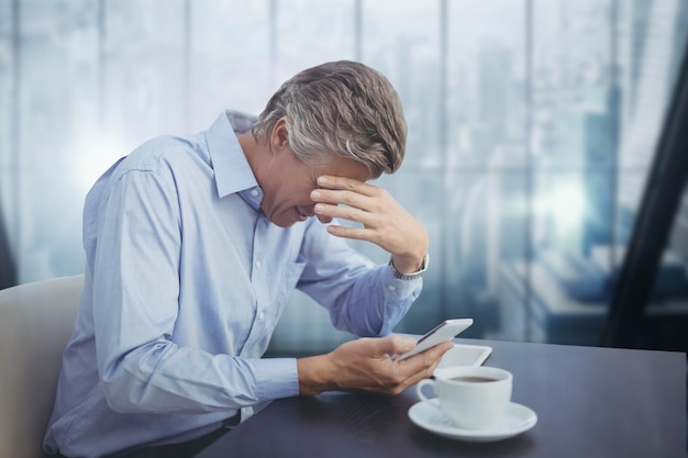 Homme d'affaires à un bureau en regardant un téléphone