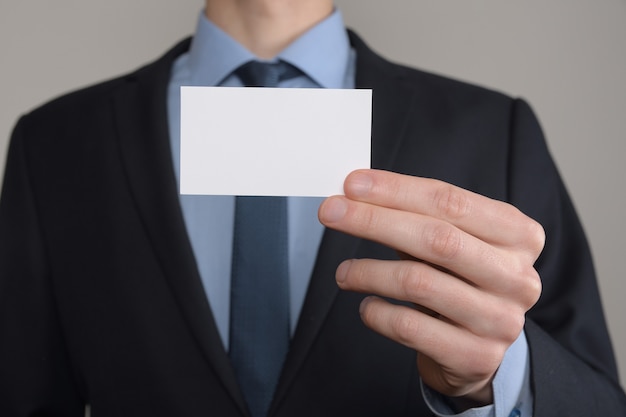 Homme d'affaires, Business Mans main tenir montrant la carte de visite gros plan sur fond gris