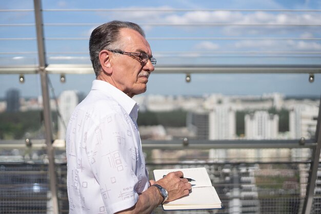 Homme d'affaires avec un cahier debout sur la terrasse du centre d'affaires