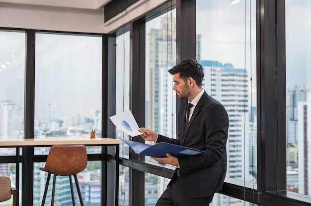 Homme d'affaires caucasien en costume debout avec la paperasse