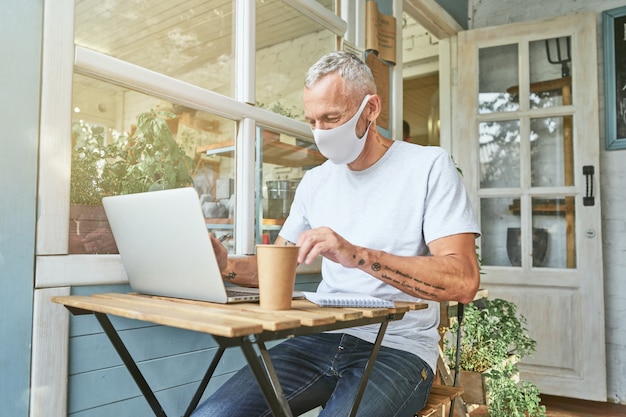 Homme d'affaires caucasien en masque de protection travaillant sur ordinateur portable