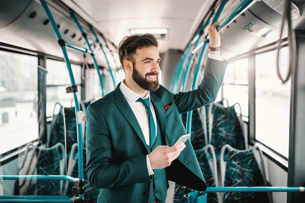 Homme d'affaires caucasien souriant en costume de conduite en bus public et à l'aide de téléphone intelligent. Vous échouez uniquement lorsque vous arrêtez d'essayer.