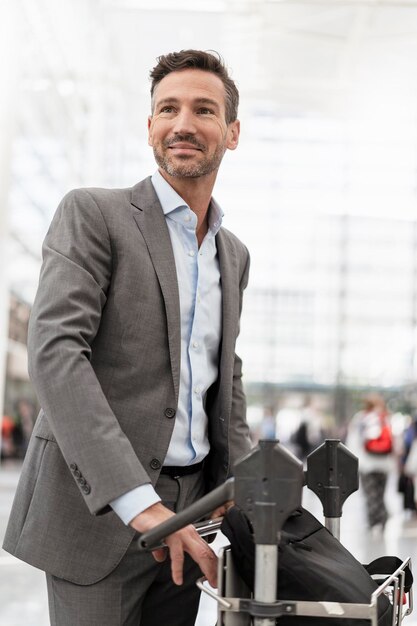 Homme d'affaires avec chariot à bagages à l'aéroport