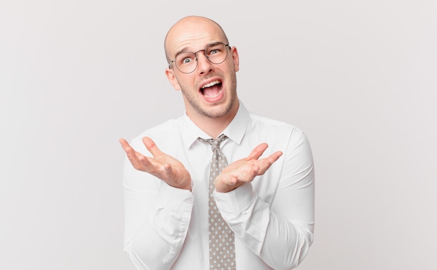 homme d'affaires chauve ayant l'air désespéré et frustré, stressé, malheureux et agacé, criant et hurlant