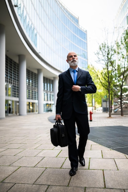 Un homme d'affaires chauve et élégant se promène avec son sac.