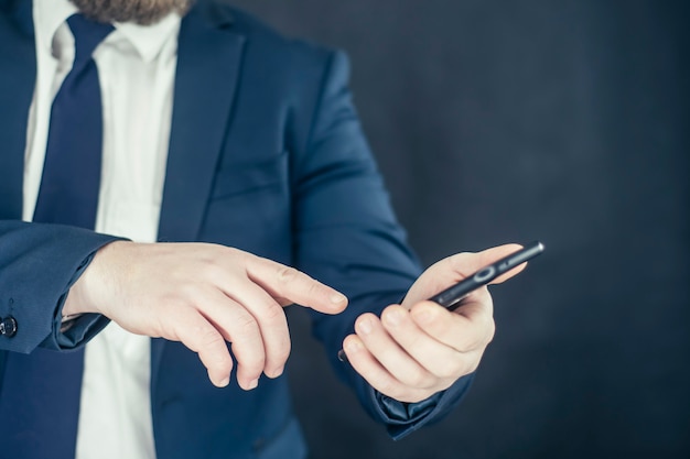 Homme d'affaires en chemise et veste bleue avec smartphone à la main.