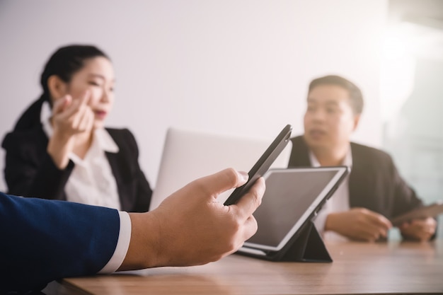 Homme d'affaires cherchant des données avec un smartphone entre la réunion de brainstorming