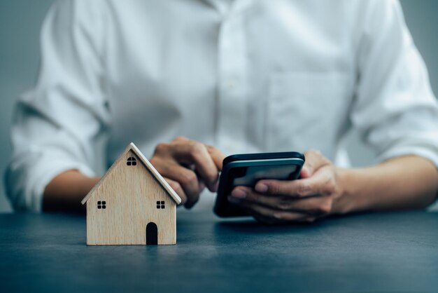 Homme d'affaires choisissant le modèle de maison et le téléphone intelligent travaillant au bureau