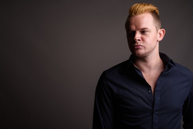 Homme d'affaires avec coiffure Mohawk et cheveux blonds sur fond gris