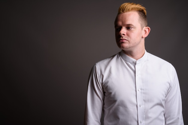 Homme d'affaires avec coiffure Mohawk et cheveux blonds sur fond gris