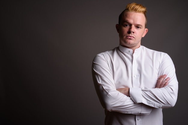 Homme d'affaires avec coiffure Mohawk et cheveux blonds sur fond gris