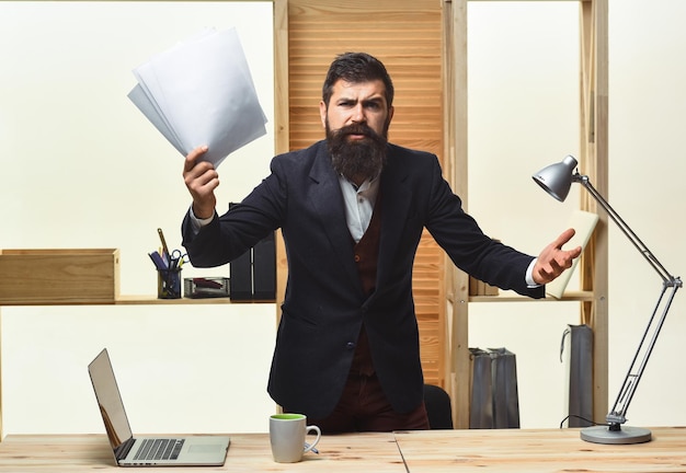 Homme d'affaires en colère criant. Portrait d'homme d'affaires barbu. Homme d'affaires en colère en costume. L'homme d'affaires tient le papier dans les mains et crie. Bel employé de bureau barbu.