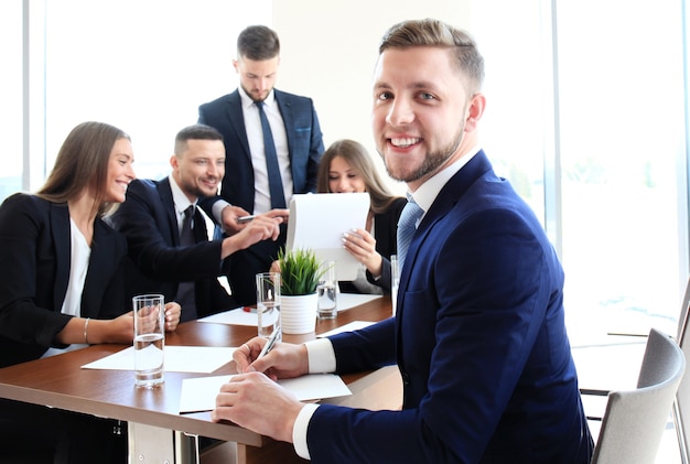 Homme d'affaires avec des collègues en arrière-plan au bureau