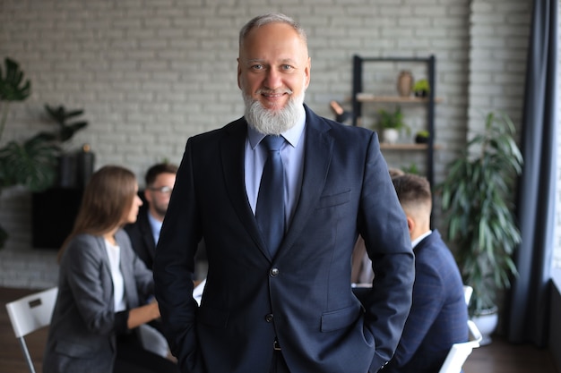 Homme d'affaires avec des collègues en arrière-plan au bureau