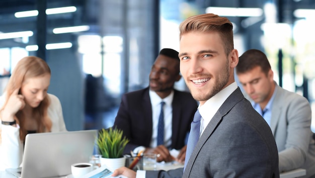 Homme d'affaires avec des collègues en arrière-plan au bureau