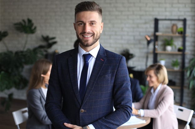 Homme d'affaires avec des collègues en arrière-plan au bureau.