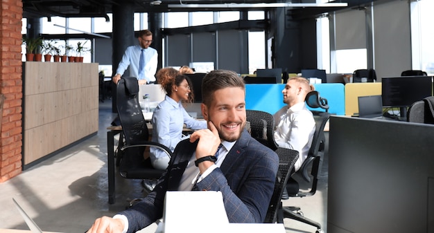 Homme d'affaires avec des collègues en arrière-plan dans un bureau moderne.