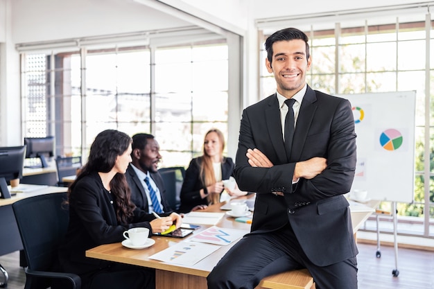 Homme d'affaires confiant caucasien sourire de bonne humeur, assis sur une table de réunion.