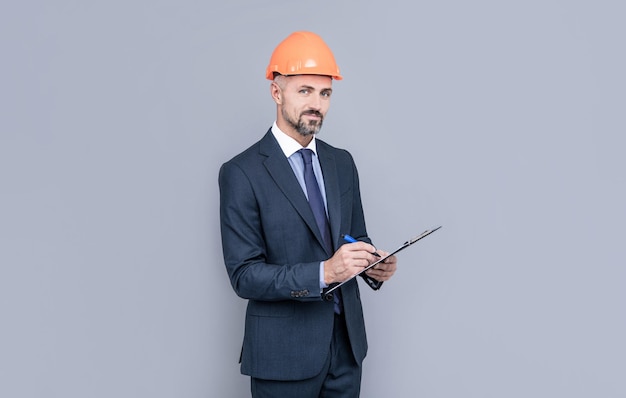 Homme d'affaires confiant dans le casque tenir dossier sécurité affaires expertise homme en casque prenant des notes